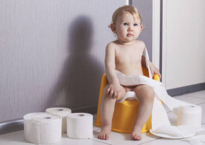 Dítě sedící na nočníku obmotané toaletním papírem